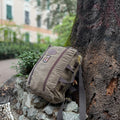 Handmade backpack leans against tree.