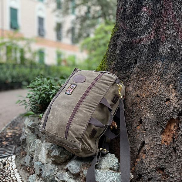 Handmade backpack leans against tree.
