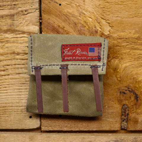 A beige mini canoe pack made of waxed canvas with brown leather straps and a red label that reads 'Frost River', 'Made in USA'.