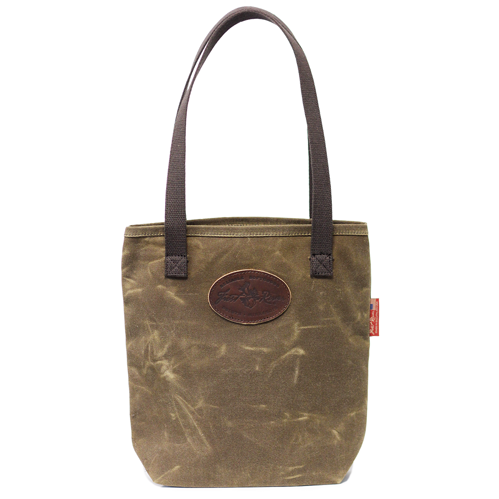 A waxed canvas tote bag with cotton web handles and a leather patch on the front.